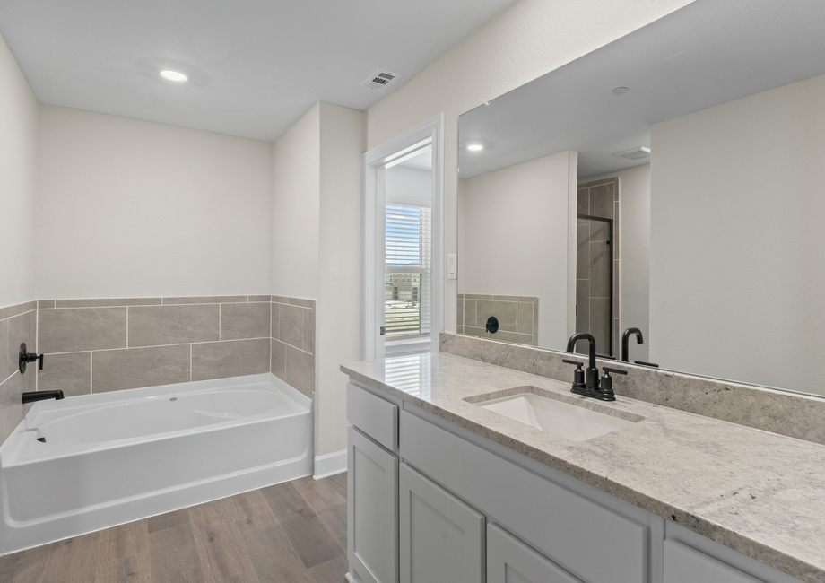 The master bathroom has a garden tub and glass, walk-in shower.