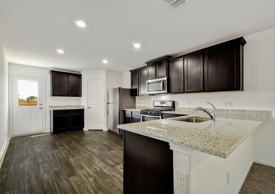 Upgraded kitchen with stunning countertops, espresso cabinetry with crown molding, and wood-style flooring. 