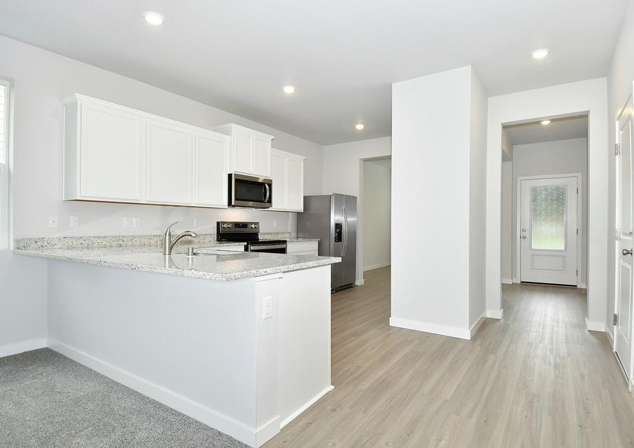 The kitchen has white cabinets and stainless steel appliances.