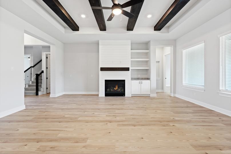 Spacious living room with beam accents and a fireplace with shiplap siding accents.