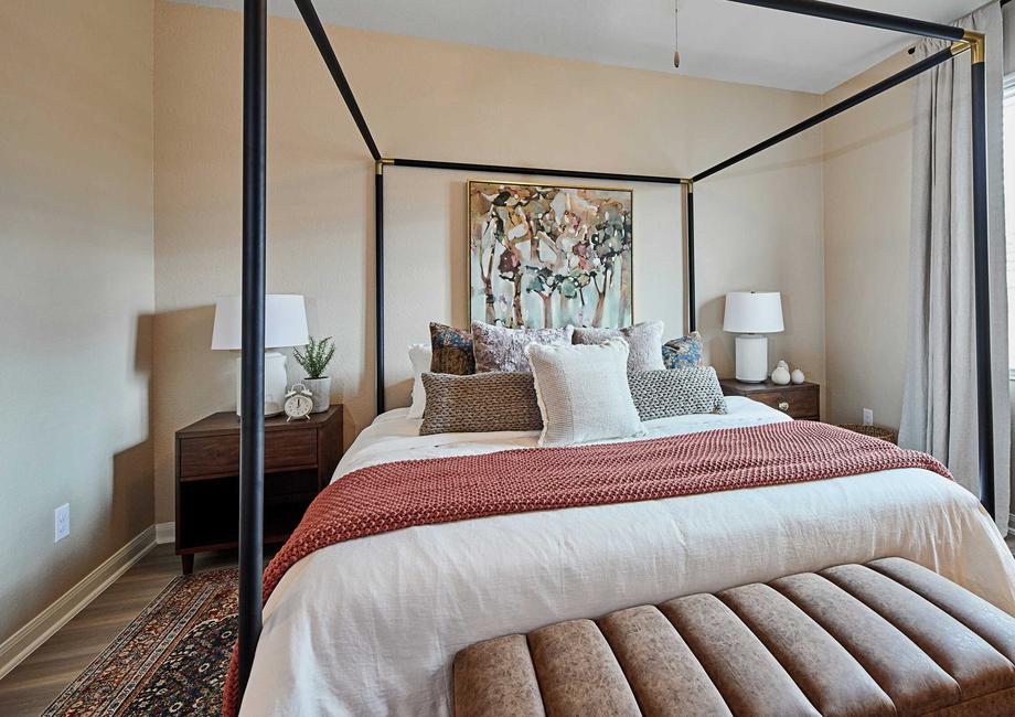 Bedroom with large cozy bed and two side tables and an ottoman 