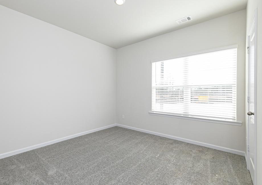 The second bedroom includes tan carpets, a closet and a window that lets in plenty of bright natural light