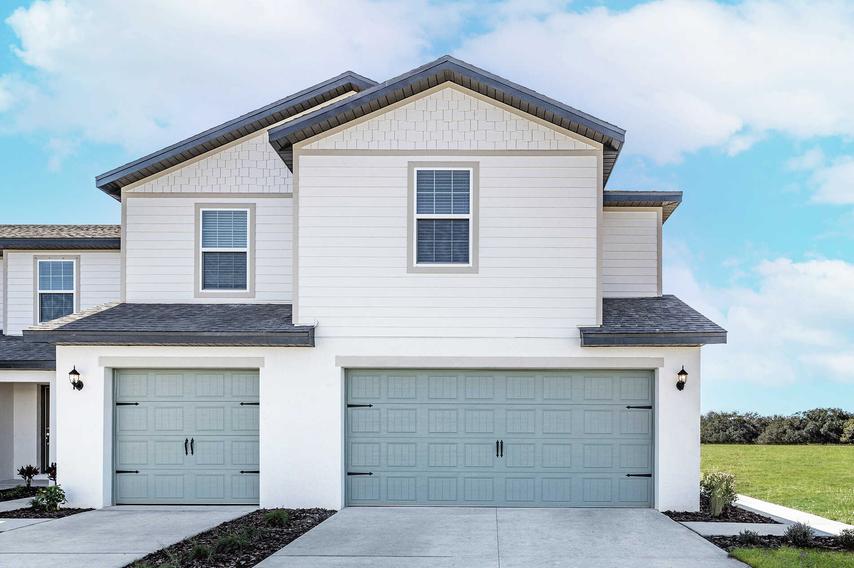 Two-story townhome with a large driveway, a two-car garage and beautiful front yard landscaping. 