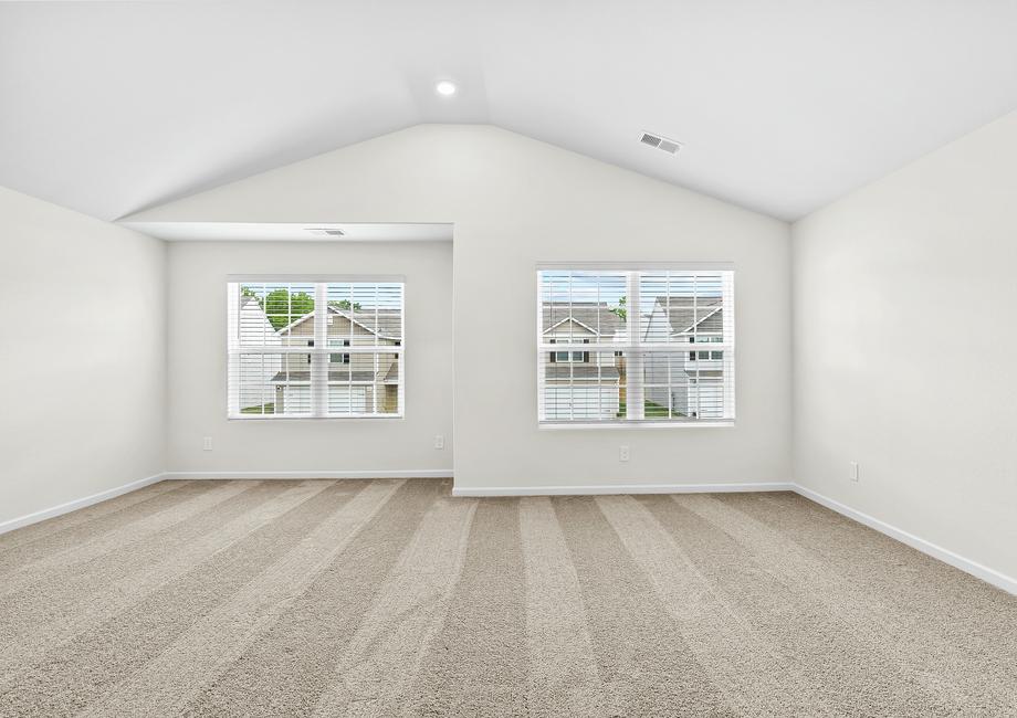 Large master bedroom with two large windows and carpet. 