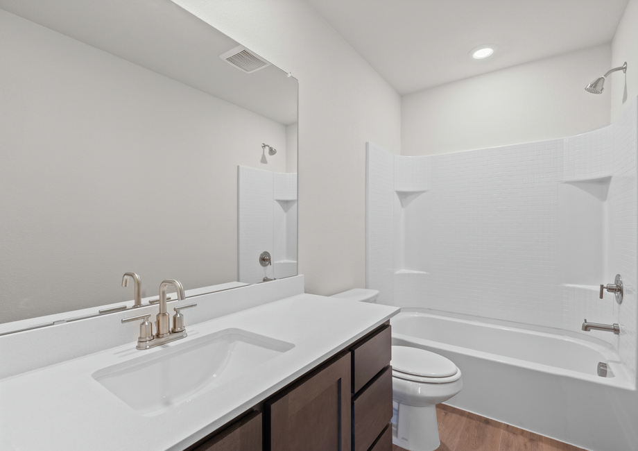 The secondary bathroom has a large vanity space and a shower-tub combo.