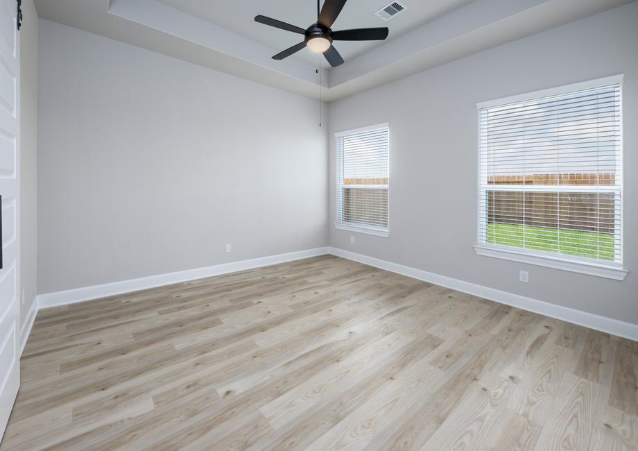 The large master bedroom has a ceiling fan and a sliding door that opens to the bathroom.