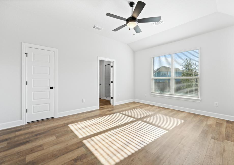 Peaceful master suite featuring high ceilings and a large picture window, flooding the room with natural light.