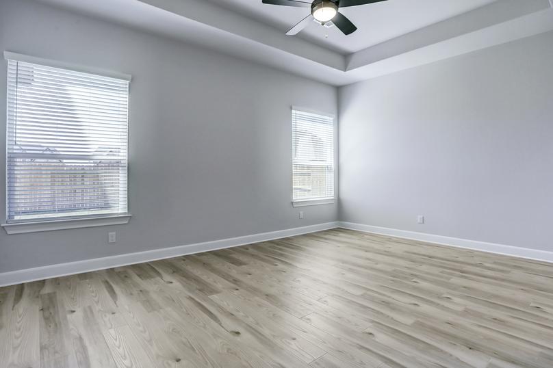 Spacious master bedroom with large windows and a ceiling fan create a peaceful retreat.