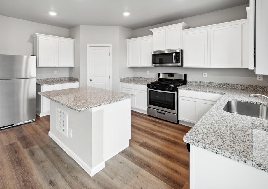 Designer kitchen with a large islands, sparkling countertops, and white cabinetry.