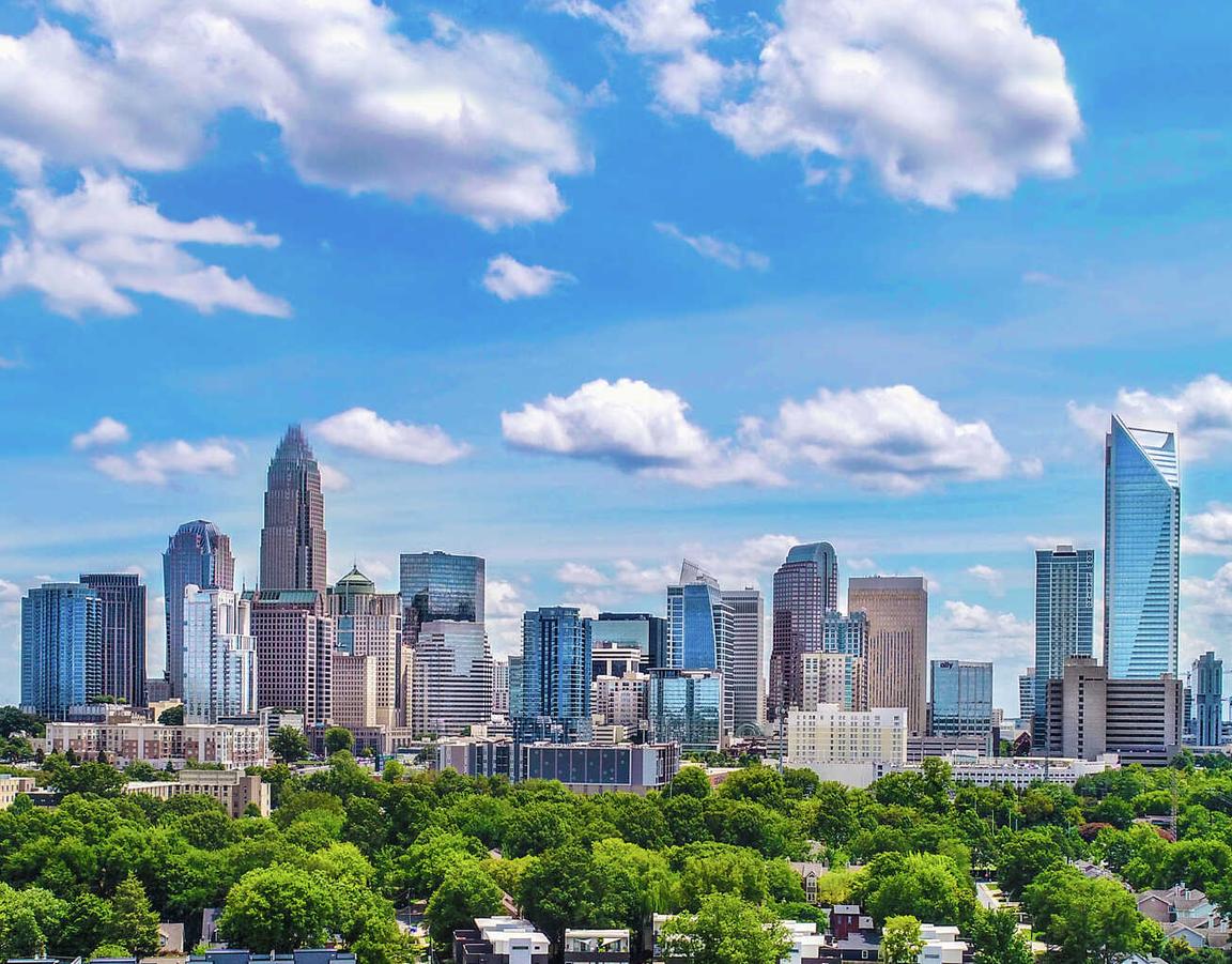 Charlotte, North Carolina aerial view of the city with residential apartment buildings in the front surrounded by Lush trees and skyscrapers off in the distance