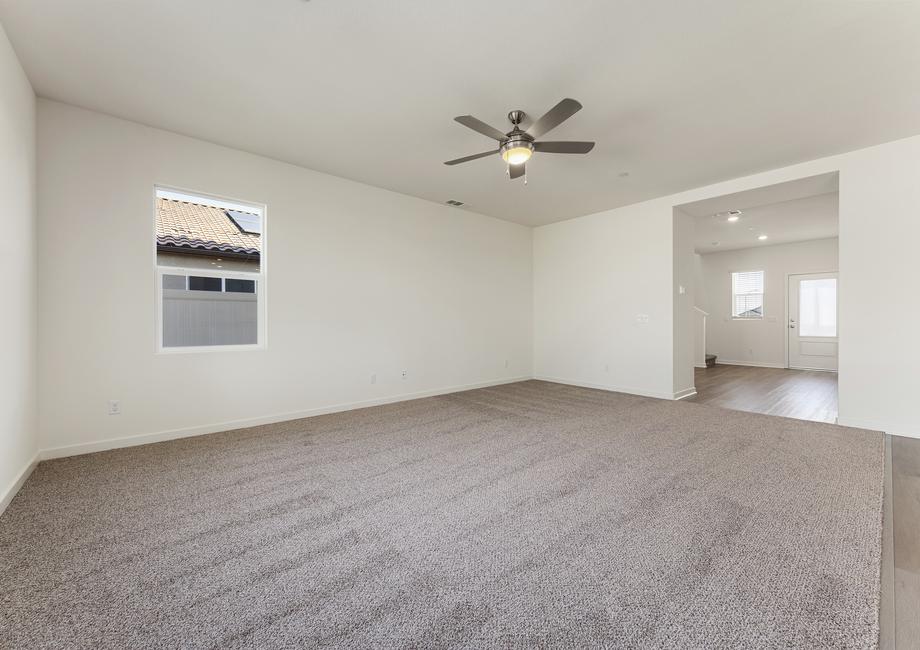 The family room is connected to the foyer and kitchen and has a ceiling fan.