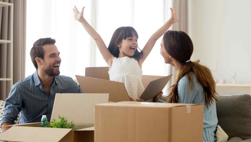 Stock image of family unpacking boxes, little girl excited with hands in the air.