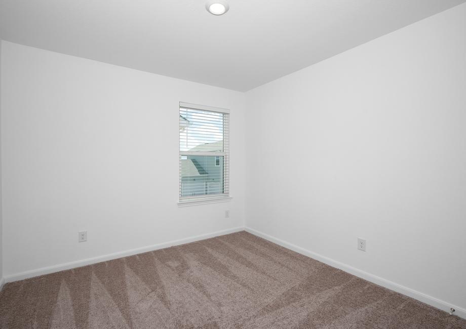 Secondary bedroom with tan carpet and a window.