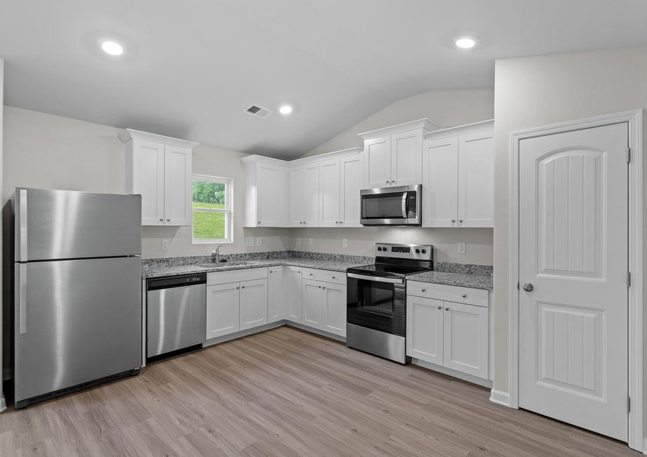 Kitchen with vinyl flooring and white cabinets.