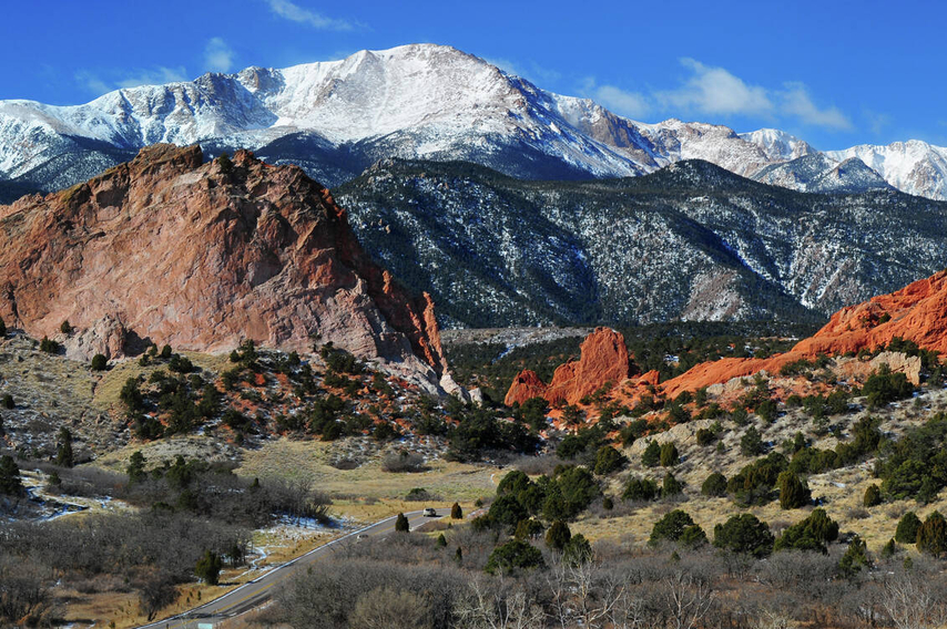 Colorado Springs, CO Pikes Peak with snowcaps, blue skies, and lush landscape in the forefront