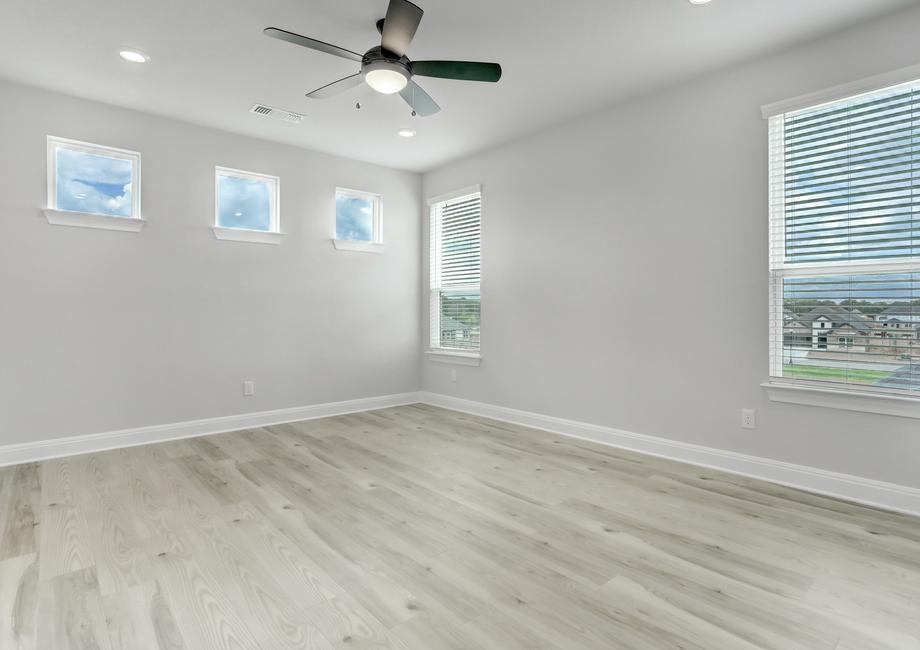 Spacious master bedroom with large windows, a ceiling fan, and wood flooring.