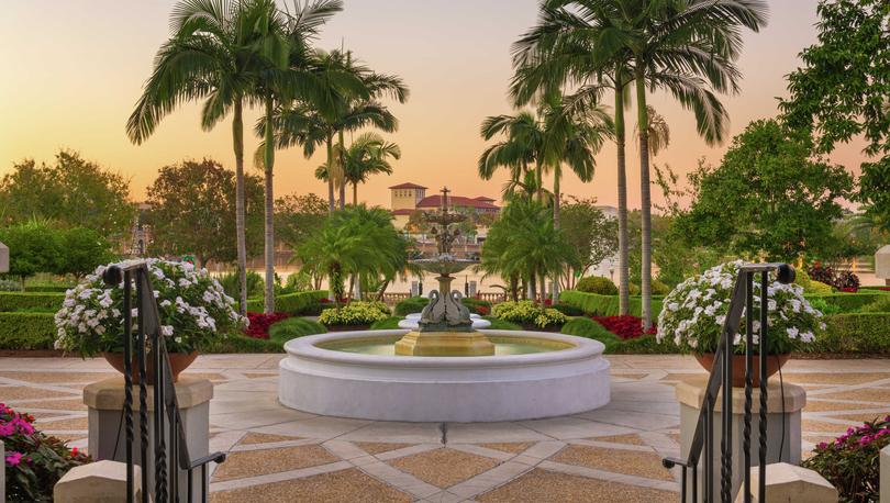 Lakeland, Florida gardens taken early evening showing a water fountain, palm trees, and red-roofed buildings in the distance