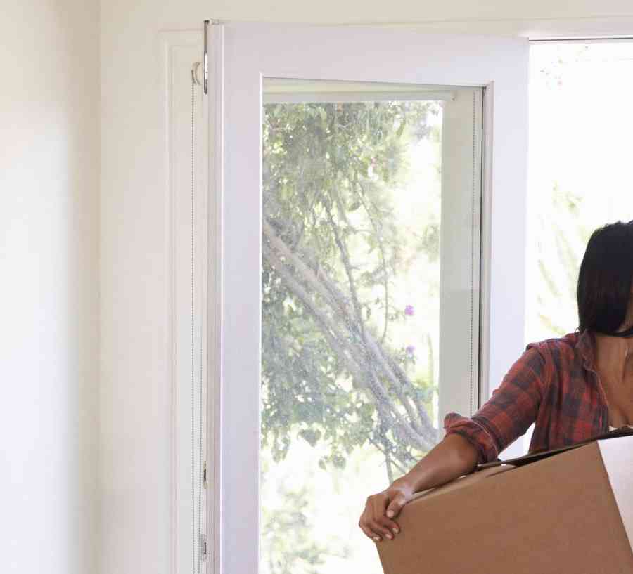 A young couple carries moving boxes into their new home.