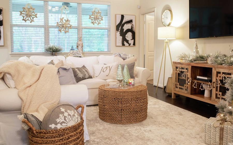 Family room completed with wicker tables, art hanging on the walls, and white couch with gray throw pillows