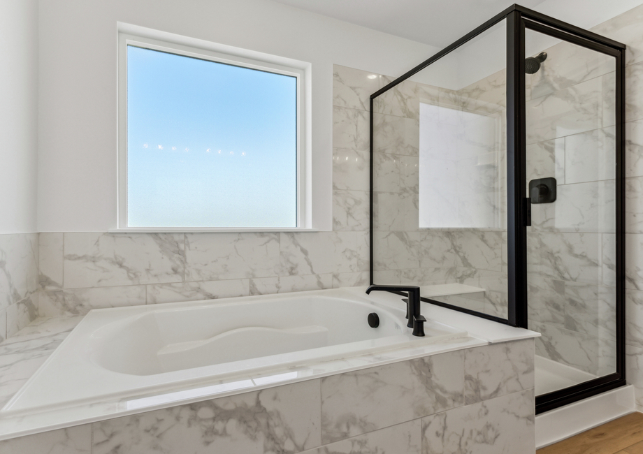 The master bathroom has a large garden tub and a spacious glass, walk-in shower.