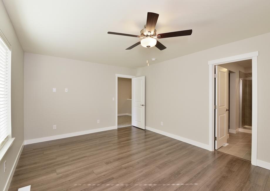 The master bedroom has plank flooring and a ceiling fan.