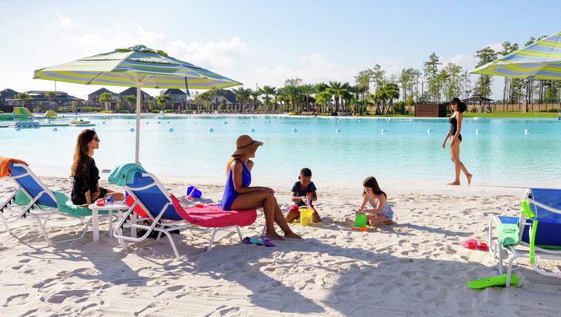 People sitting by a lagoon on sand.