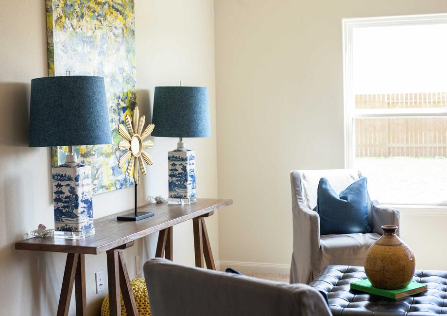 Two decorative lamps with blue shades sitting on a wooden table and a painting hanging on the wall behind them.