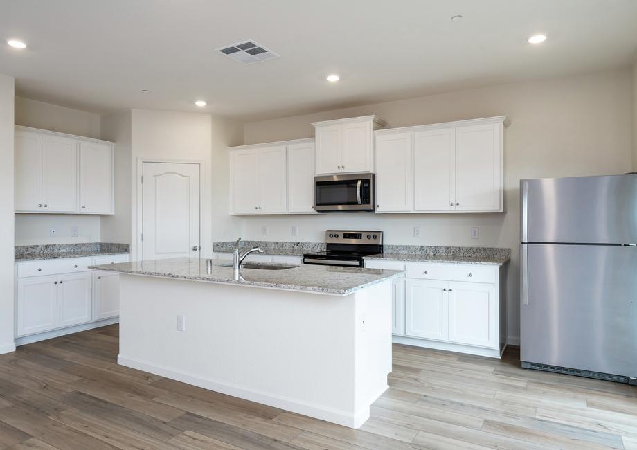 The kitchen has stainless steel appliances and plank flooring.