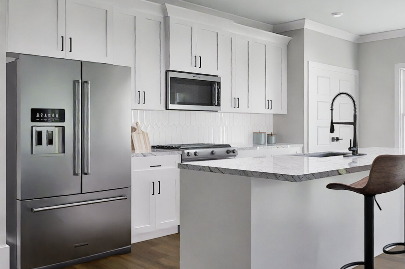 A modern kitchen featuring stainless steel appliances and sleek white cabinets.