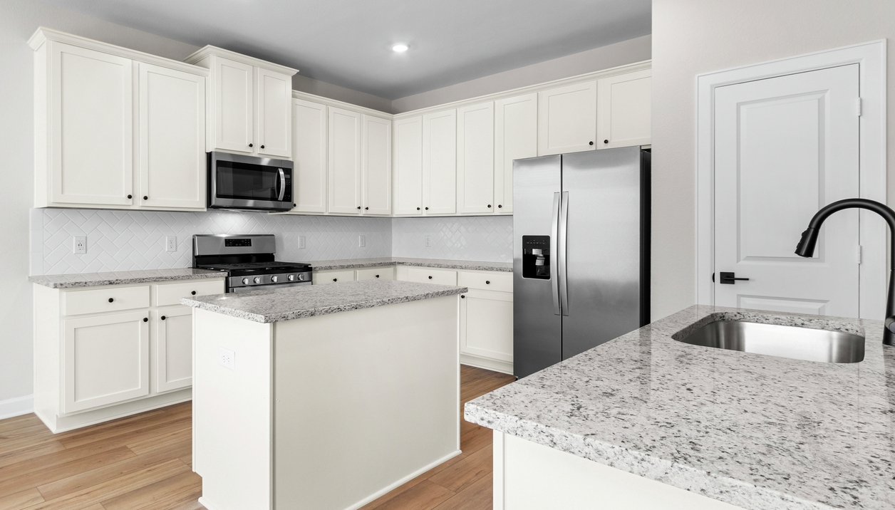Kitchen with white cabinetry, tile backsplash and granite counters.