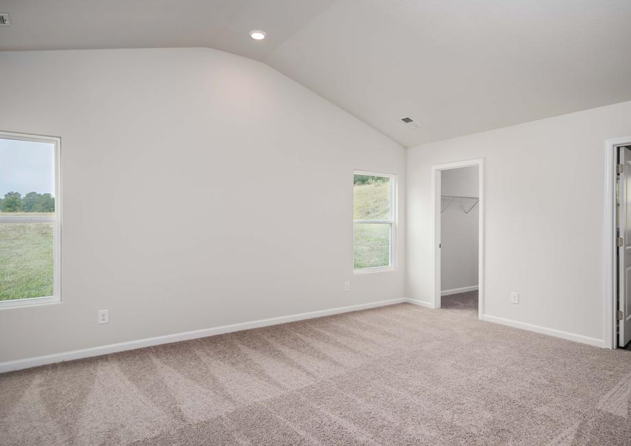 Master bedroom with tan wall, tan carpet and two windows.