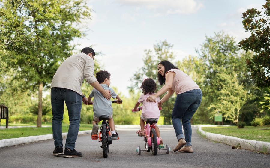 Parents teaching their two children to ride a bike.