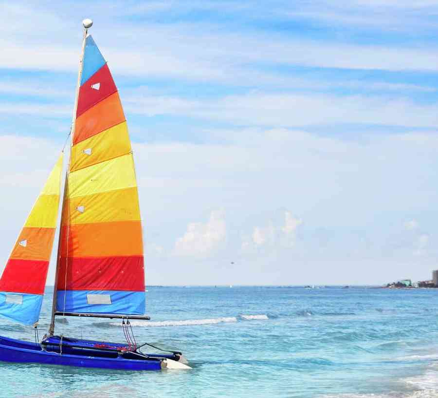 Fort Myers, Florida catamaran sailboat with rainbow sails on blue waters with dark blue skie and white clouds