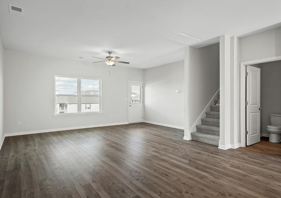 The spacious family room includes a ceiling fan and plank flooring.