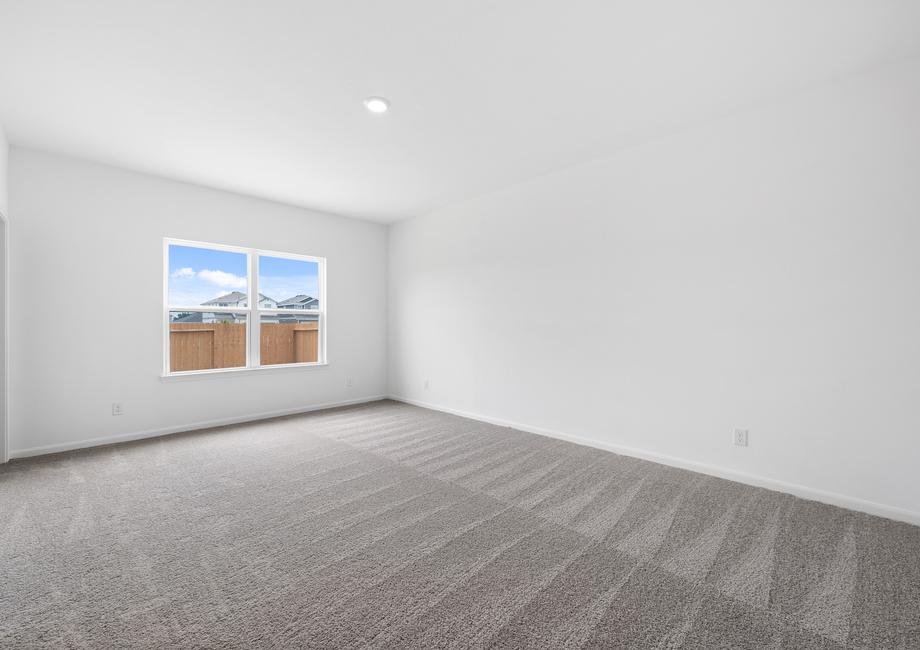 Expansive master bedroom with tan carpet and windows.
