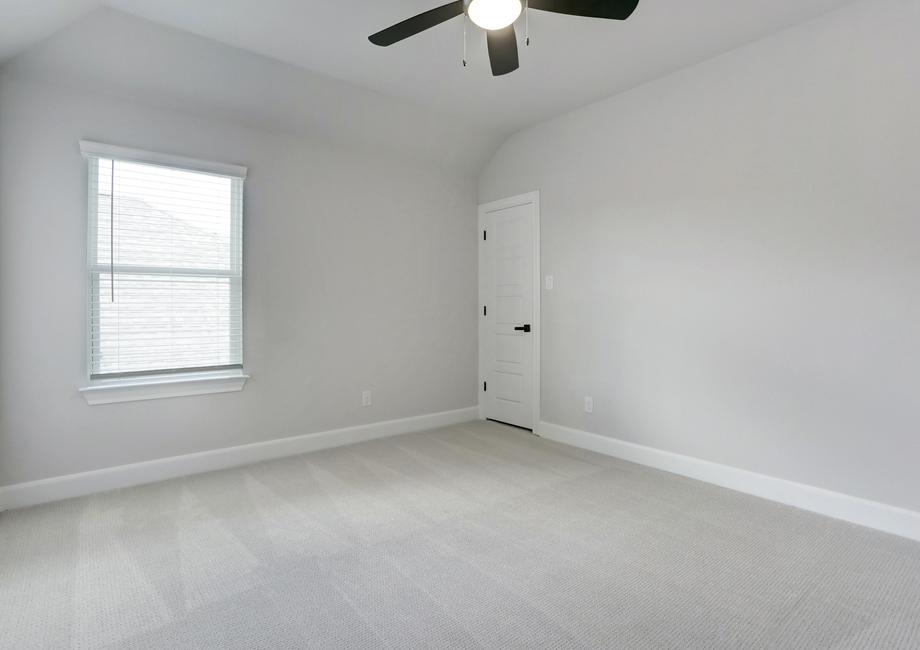 Guest bedroom with a ceiling fan and carpet.
