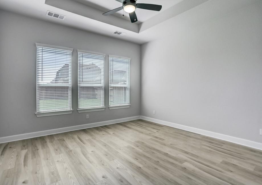 Expansive master bedroom with three large windows that allow natural light in.