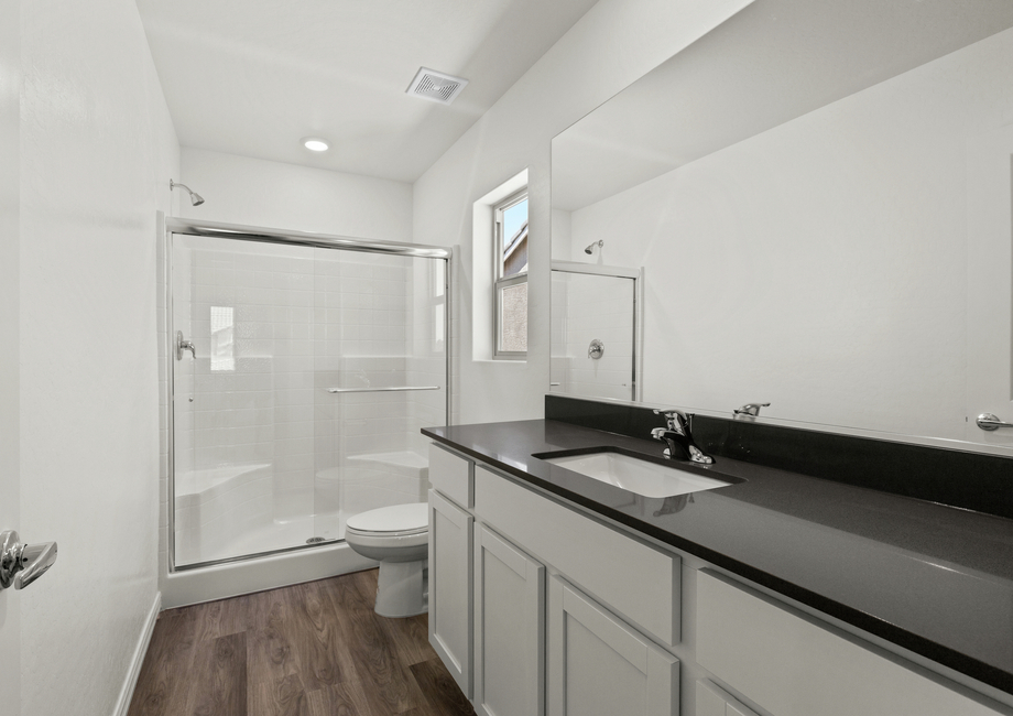 The master bathroom has a large vanity with plenty of counter space and a glass, walk-in shower.