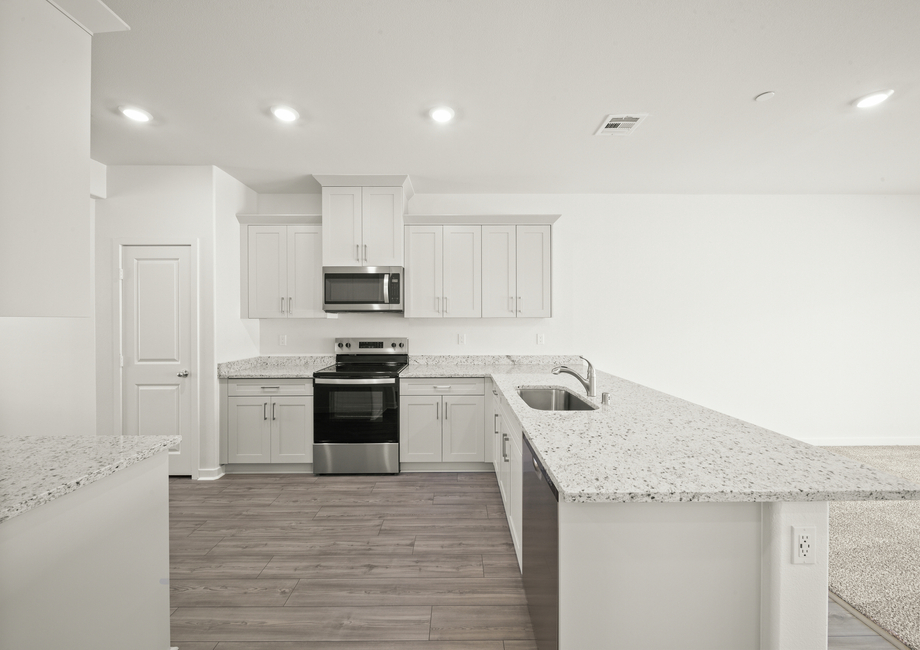 The kitchen has plank flooring and stainless steel appliances.