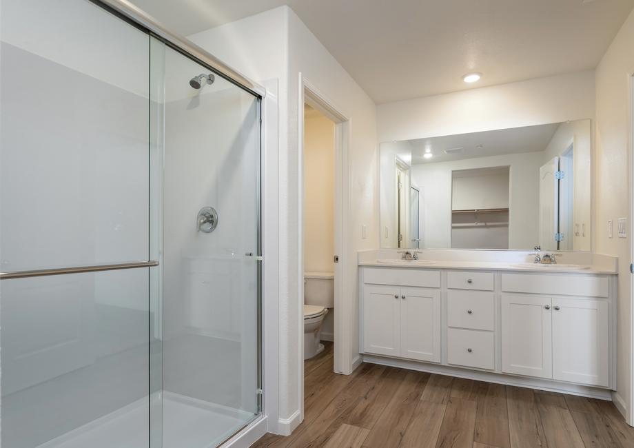 The master bathroom has a dual sink vanity and step in shower.