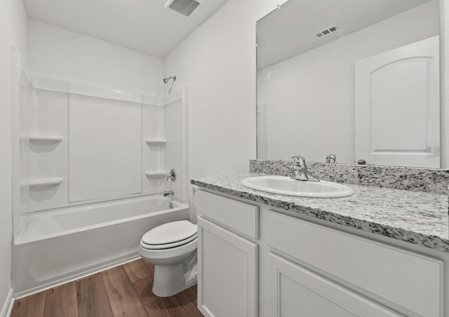 The secondary bathroom has white cabinets and granite countertops