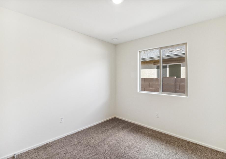 Guest bedroom with tan carpet and recessed lighting.