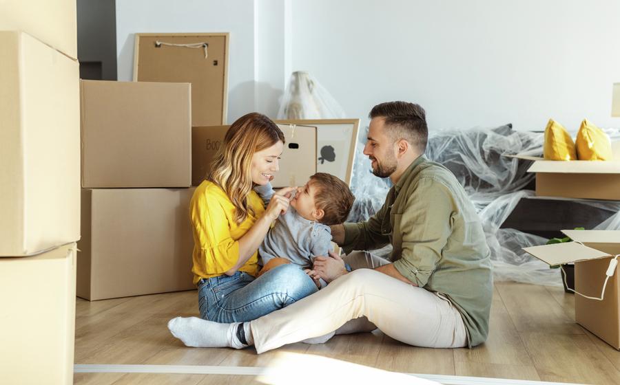 Couple sitting on the floor of their new home with their son between them.