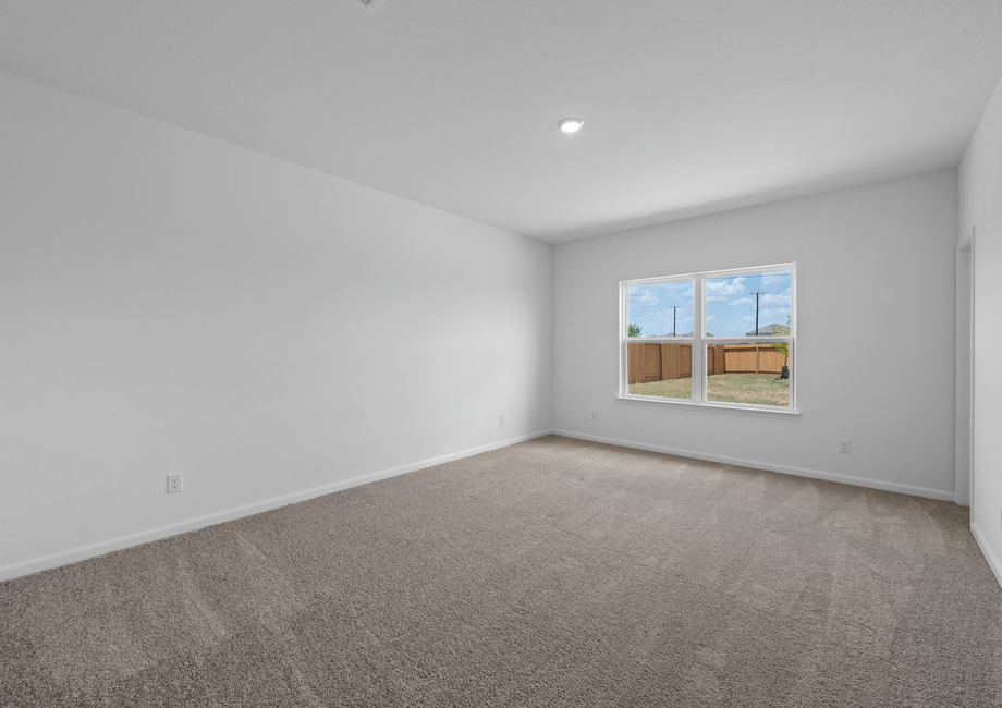 Master bedroom with a large window overlooking the private backyard