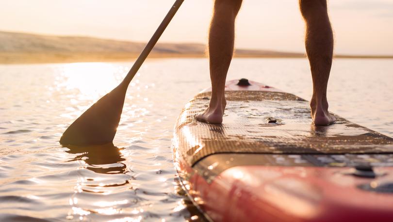 Person paddleboarding on the lake at sunset.