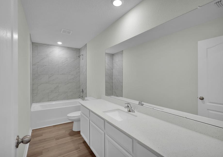 The secondary bathroom features a spacious vanity and a large soaker tub.