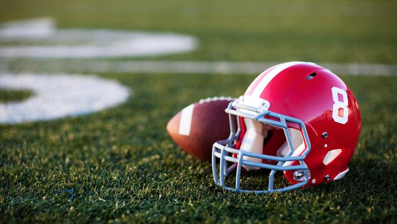 Photo of red football helmet on field.