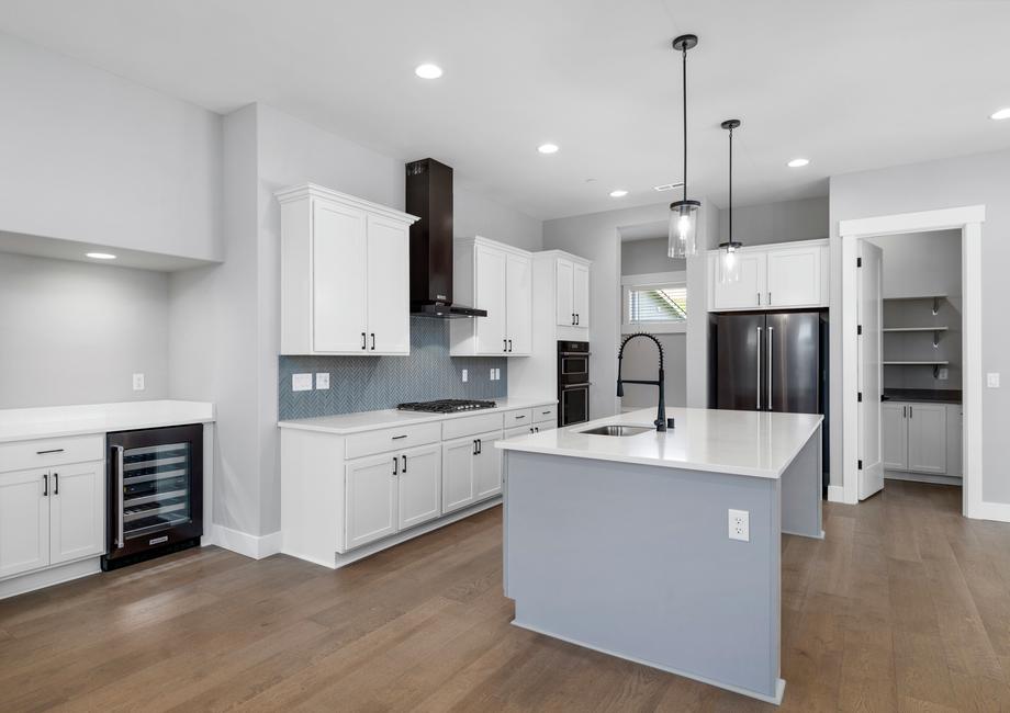 This unbelievable kitchen showcases stunning quartz countertops, back stainless steel KitchenAid appliances and a wine fridge.