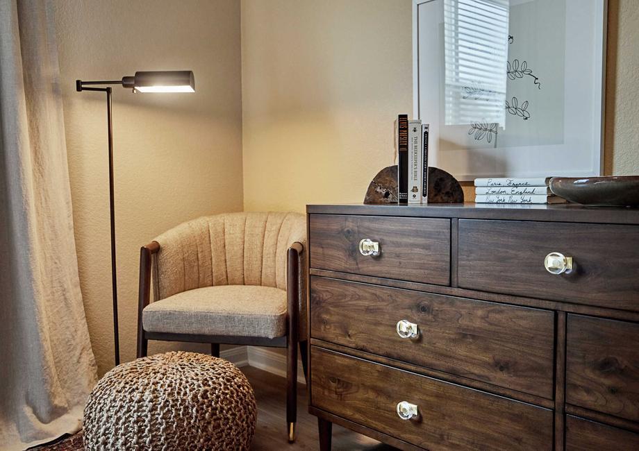 Staged sitting area with a brown chair and wooden drawers.