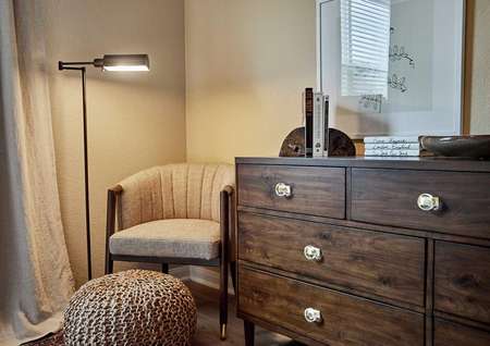 Staged sitting area with a brown chair and wooden drawers.